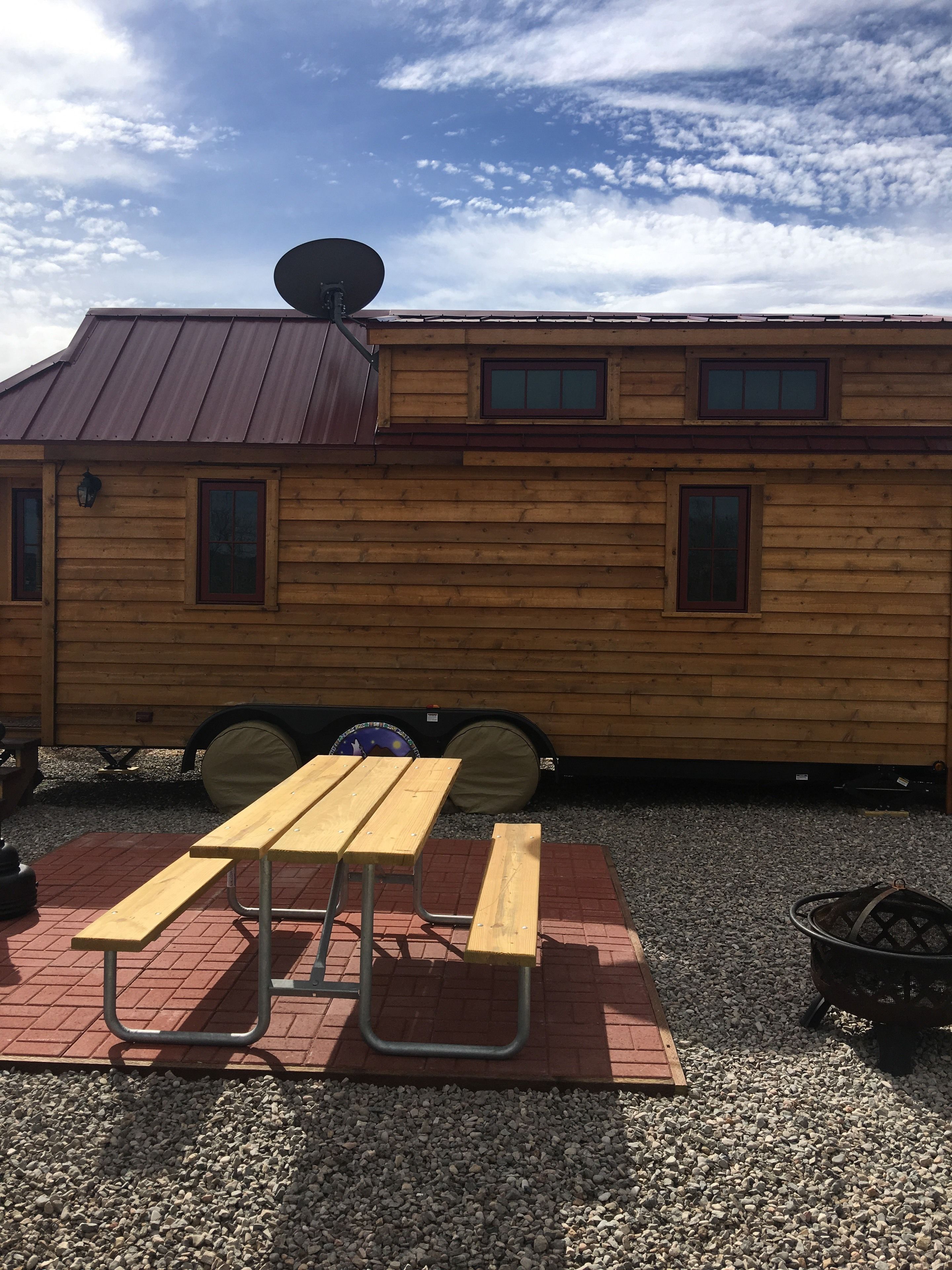 Eine Holzhütte mit Picknicktisch, Satellitenschüssel und einer kleinen Sitzgelegenheit im Freien.
