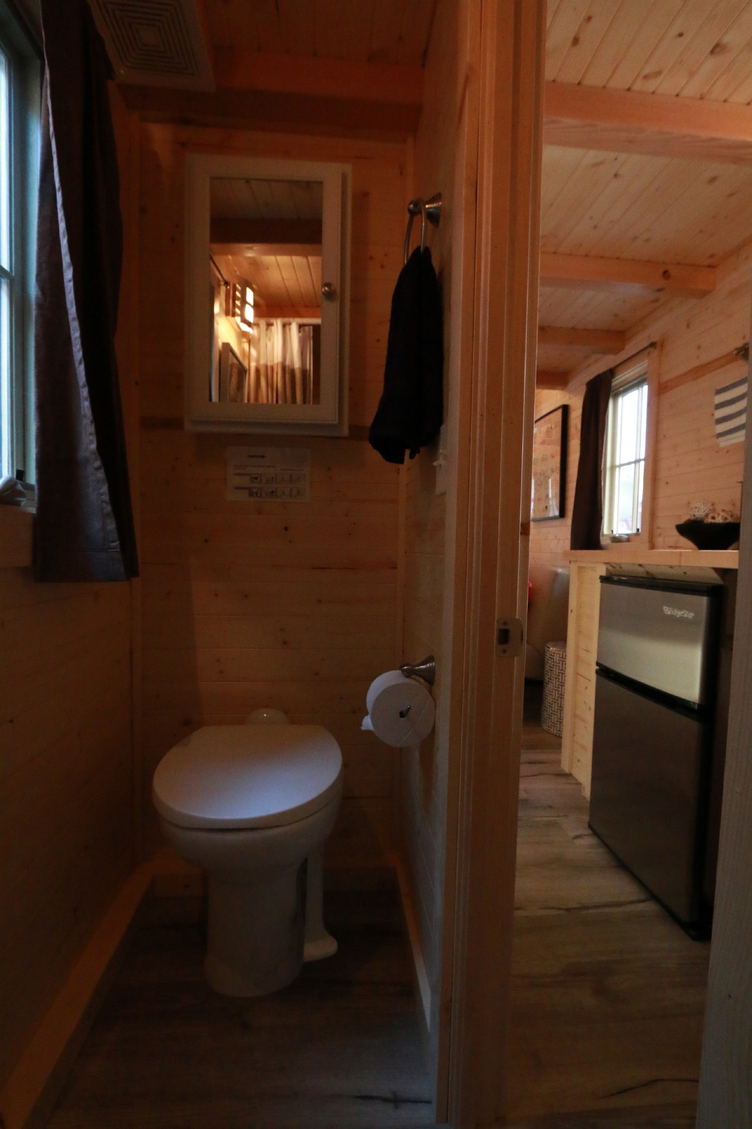 A compact wooden cabin with a small bathroom containing a toilet and a sink.