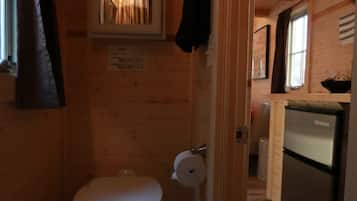 A compact wooden cabin with a small bathroom containing a toilet and a sink.