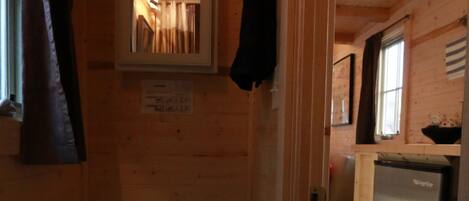 A compact wooden cabin with a small bathroom containing a toilet and a sink.