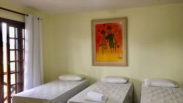 A room with two single beds, a painting on the wall, and a window with curtains.