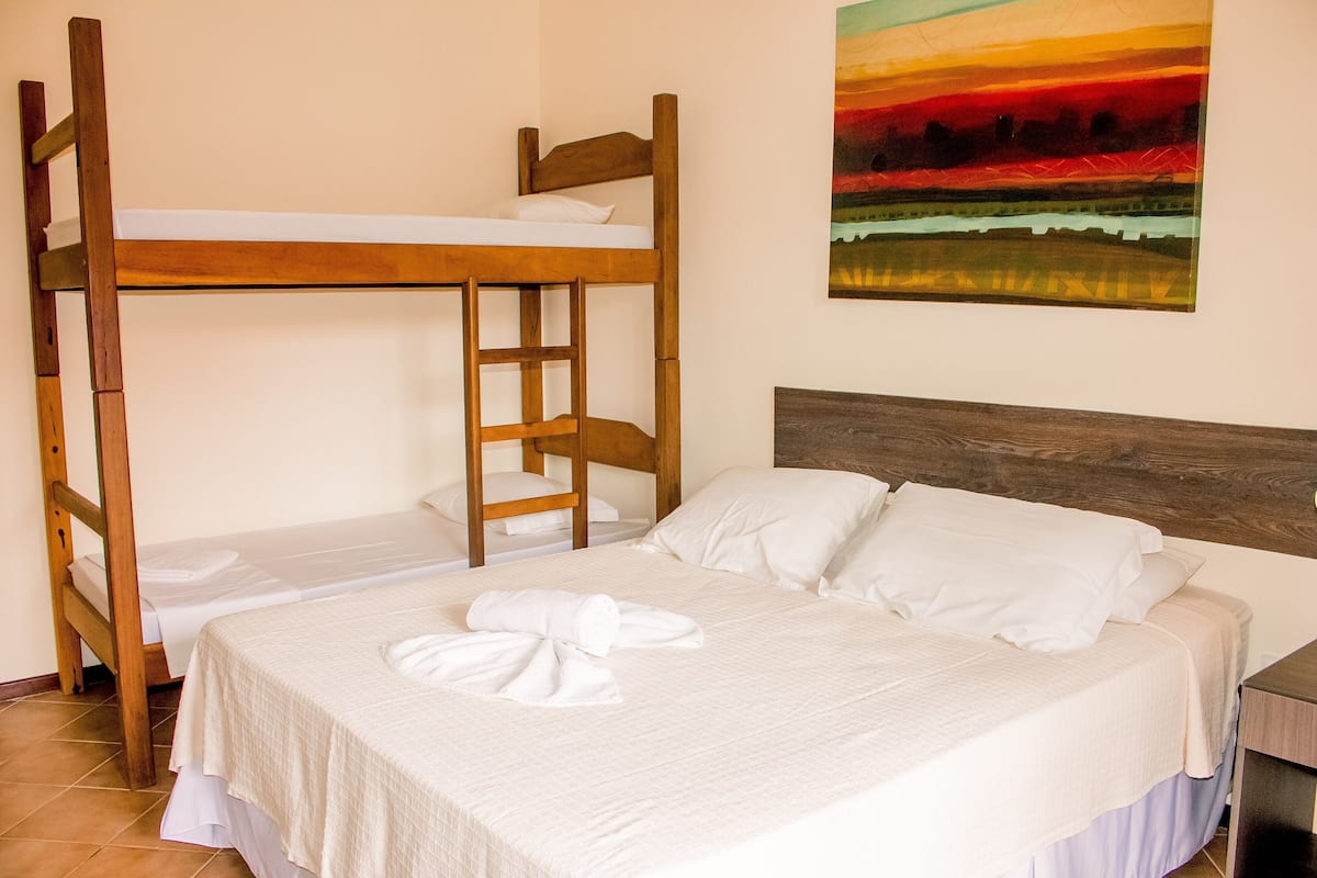 A room with bunk beds, a wooden headboard, and a painting on the wall.
