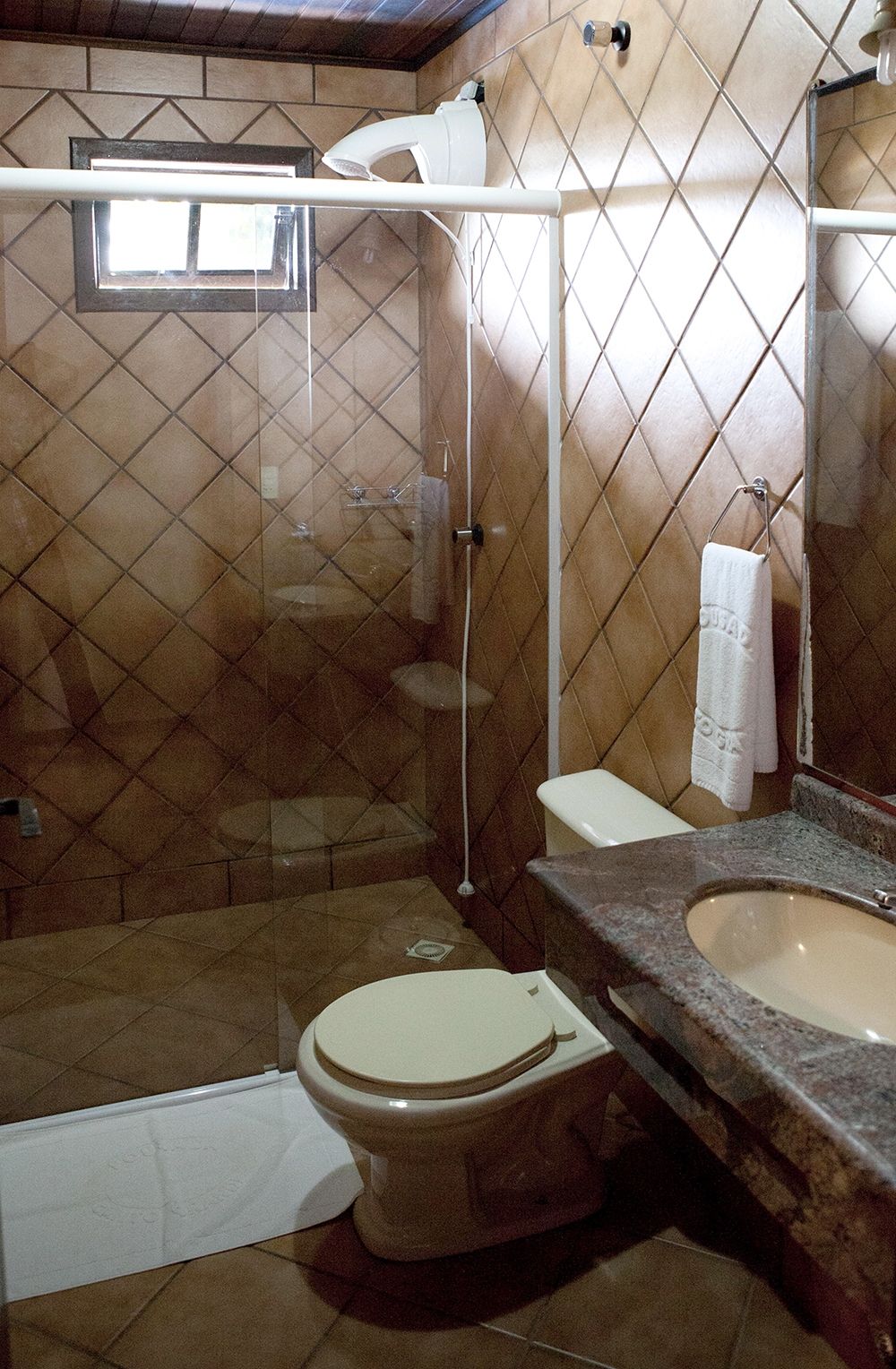 A bathroom with a shower, toilet, sink, and a mirror.