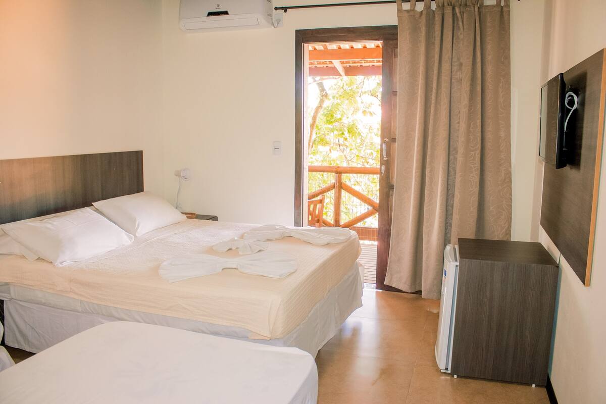 A hotel room with a bed, a small desk, and a TV on the wall.