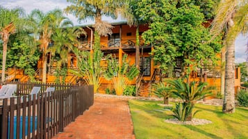 Guests can enjoy stunning views from the two-story building's balconies, surrounded by a beautifully maintained garden with tropical plants.