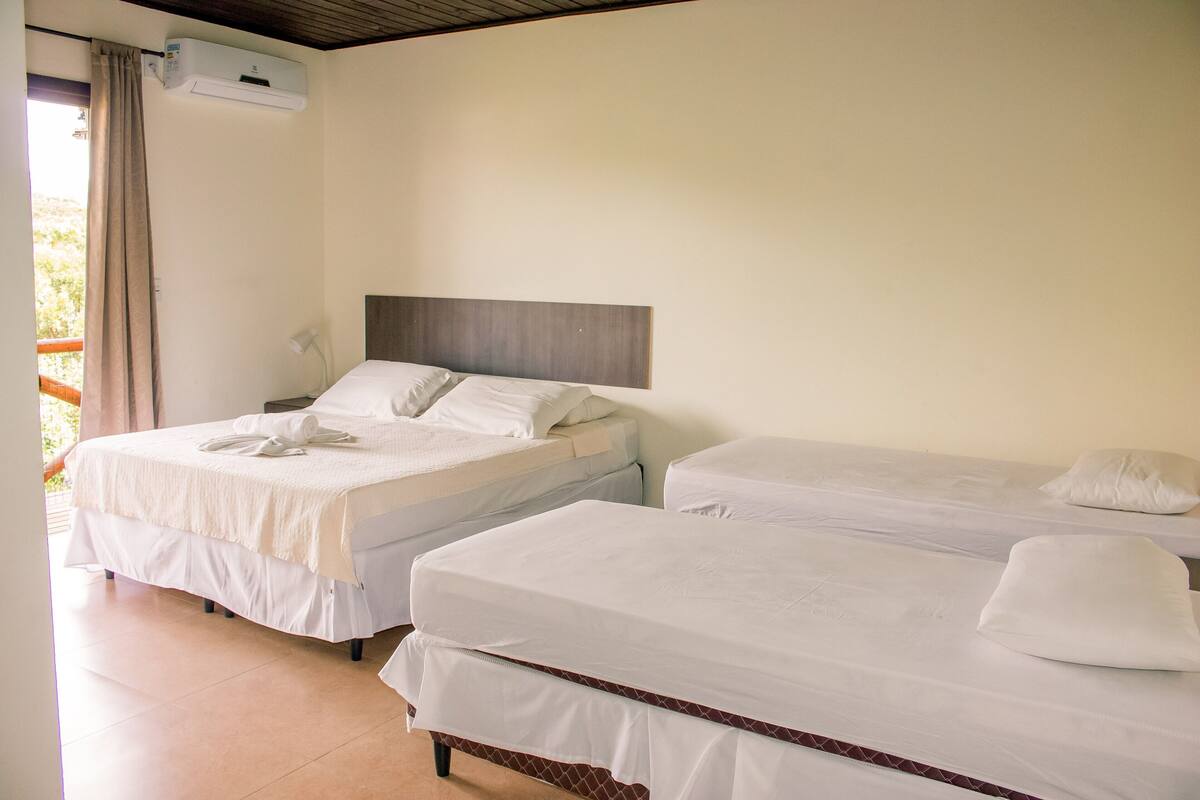 A hotel room with two beds, a wooden headboard, and an air conditioning unit.