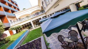 Une cour avec une piscine, des sièges extérieurs et un espace abrité avec des parasols.