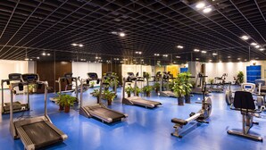 Une salle de sport équipée de tapis de course, de vélos d’appartement et d’appareils de musculation.