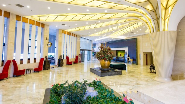Un hall d’entrée spacieux, doté d’un haut plafond, de grandes fenêtres et d’une composition florale centrale.