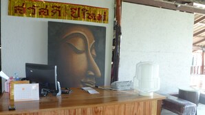 A reception desk with a computer, calendar, and a large Buddha painting. - Sun Moon Star Resort Koh Phangan (Ko Pha-ngan)