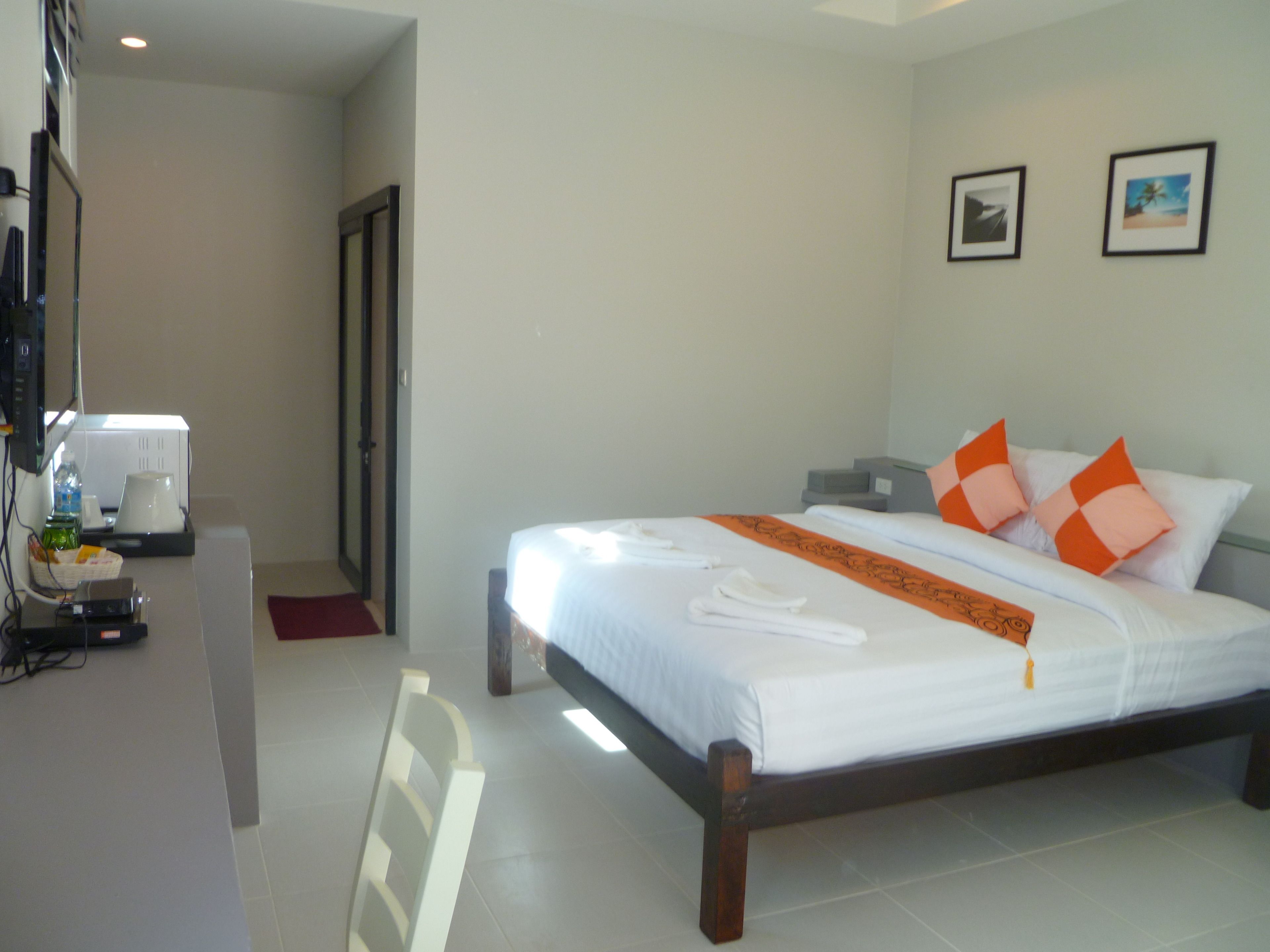 Habitación de hotel con cama, escritorio con cafetera y dos cuadros en la pared.