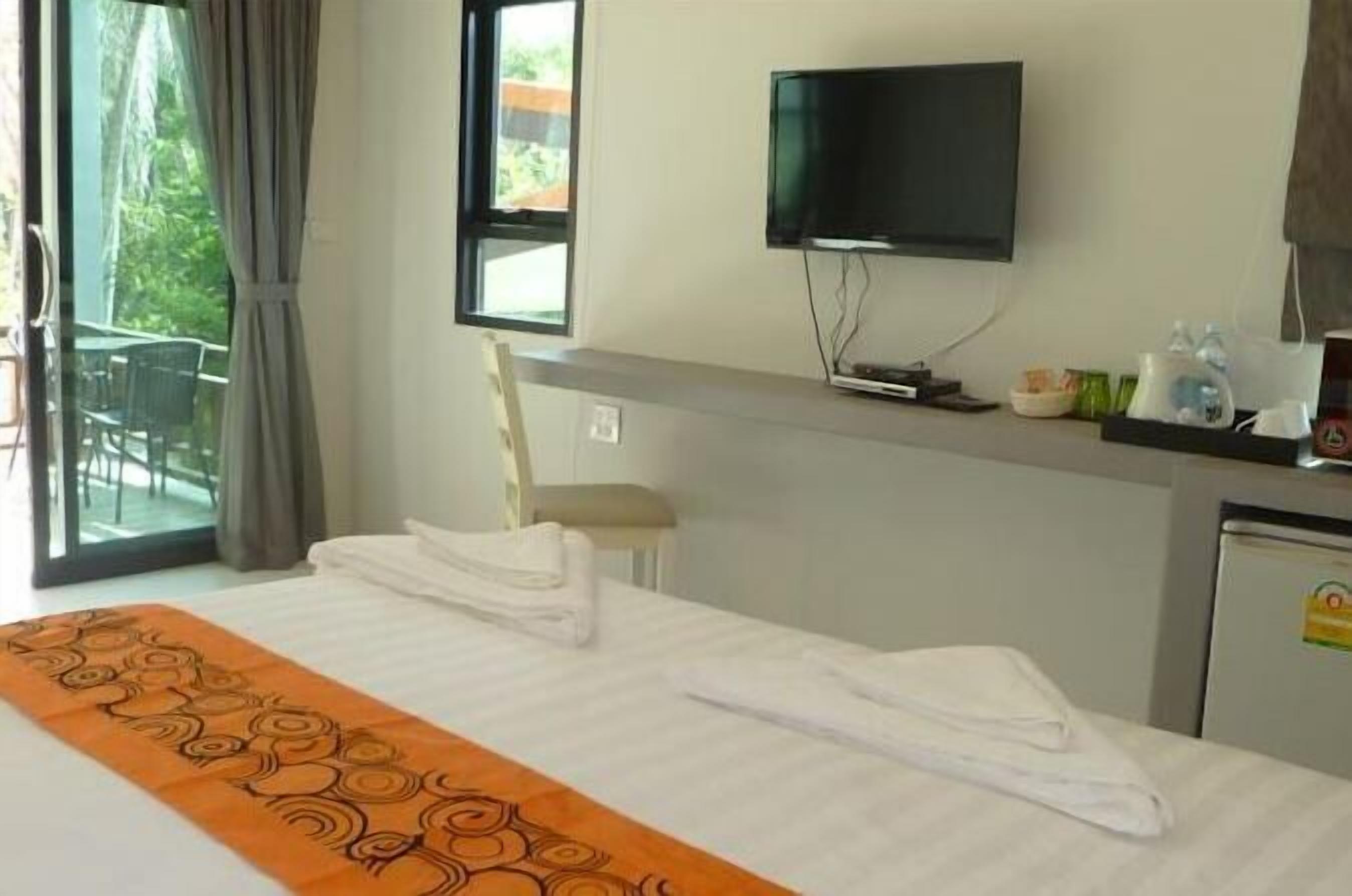 Habitación de hotel con cama, televisión, escritorio con ordenador y vistas a zonas verdes.