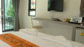 Habitación de hotel con cama, televisión, escritorio con ordenador y vistas a zonas verdes.