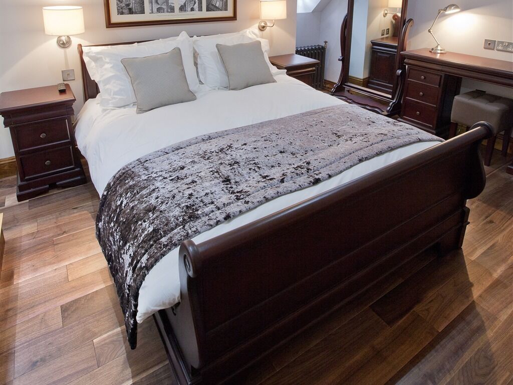 A neatly made bed with a patterned blanket, wooden headboard, and bedside tables with lamps.