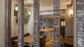 A dining area with wooden tables and chairs, a patterned carpet, and a bookshelf in the background. - The New Inn (Dorchester)