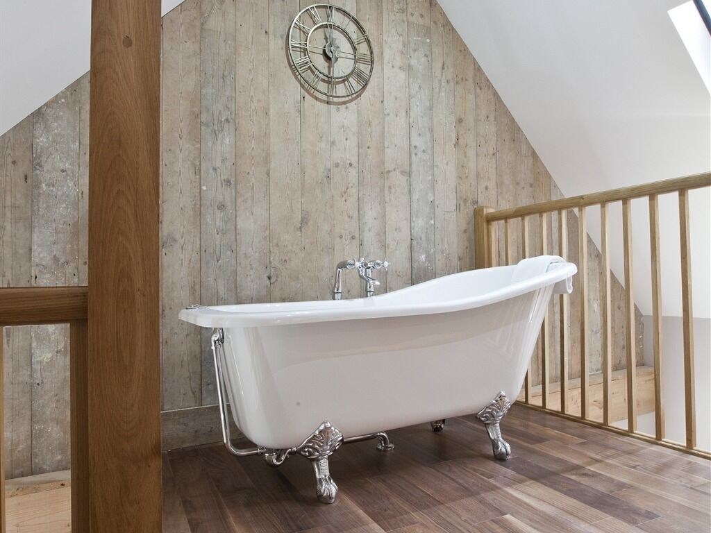 A freestanding bathtub in a room with wooden walls and a wooden floor.