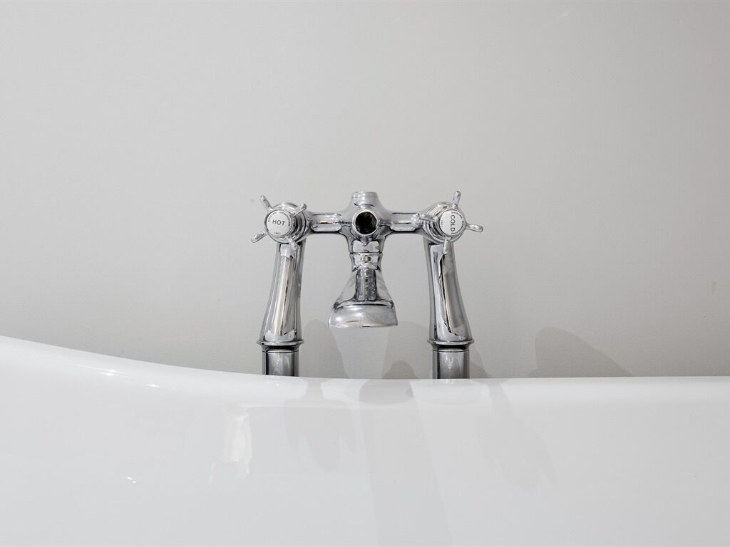 A bathroom with a white bathtub and a chrome faucet.