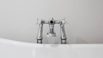 A bathroom with a white bathtub and a chrome faucet.