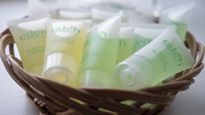 Un panier en osier contenant plusieurs tubes de shampoing et d’après-shampoing de la marque Eden.