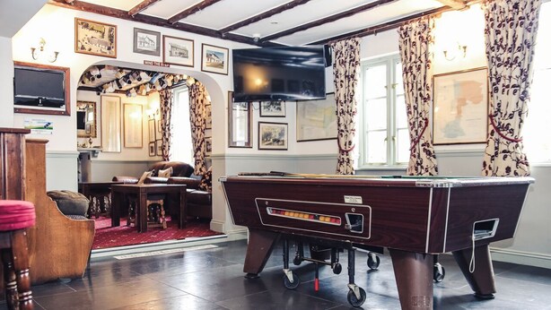 Une salle de billard équipée d’une table de billard, de meubles en bois et de tableaux encadrés aux murs.