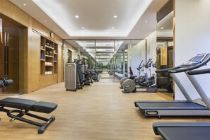 A modern gym with various exercise equipment, including treadmills and weight machines, arranged in a spacious layout. - Wanda Realm Harbin (Harbin)