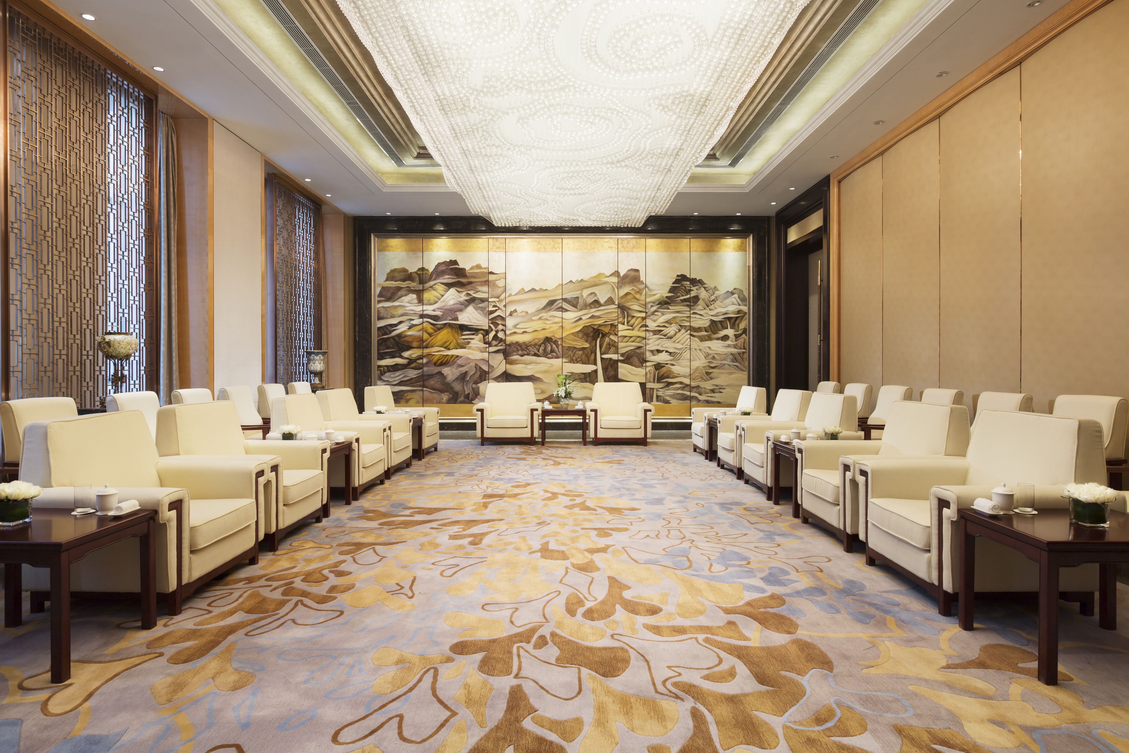 A conference room with a patterned carpet, beige chairs, and a large wall mural.