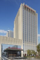 Un hotel alto de diseño moderno, con un llamativo letrero de 'Wanda Realm' en la parte superior.