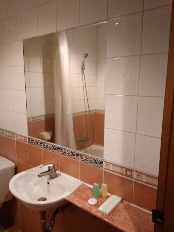 A bathroom with a sink, mirror, shower, and a decorative tile border.
