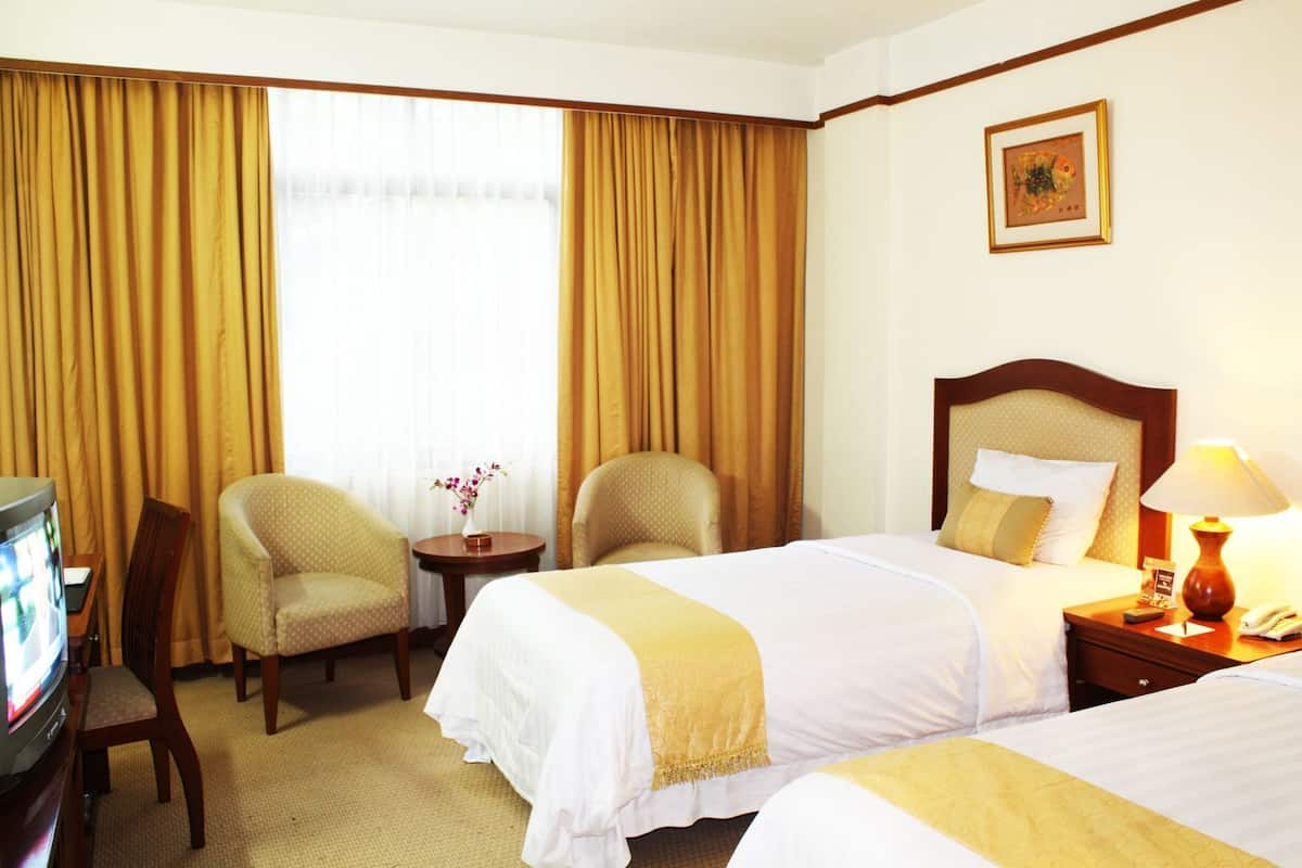 A hotel room with two beds, a TV, a desk, and a chair.