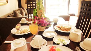 A dining table set with plates of food, a teapot, cups, and a floral centerpiece.