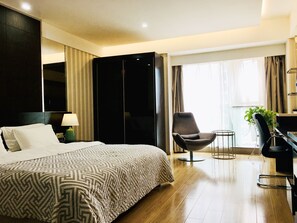 A hotel room with a large bed, a chair, a desk, and a plant. - Nanjing Kaibin Apartment - Kairun No. 5 (Nanjing)