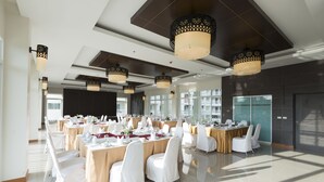 A spacious conference room with multiple tables set for dining, large windows, and modern ceiling lights. - Chanalai Hillside Resort, Karon Beach (Karon)