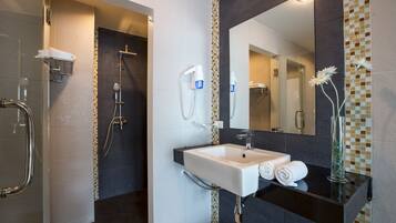 A modern bathroom with a glass shower enclosure, a white sink, and a large mirror with a decorative tile backsplash.