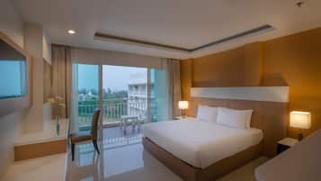 Habitación de hotel con una cama grande, mesitas de noche, televisión, balcón con una silla y vistas a la ciudad.