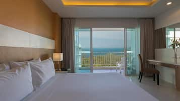 Habitación de hotel con una cama grande, un escritorio, una silla y un balcón con vistas al mar.
