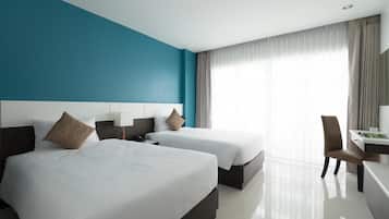 A hotel room with two beds, a desk, and a chair.