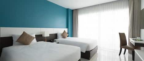 A hotel room with two beds, a desk, and a chair.