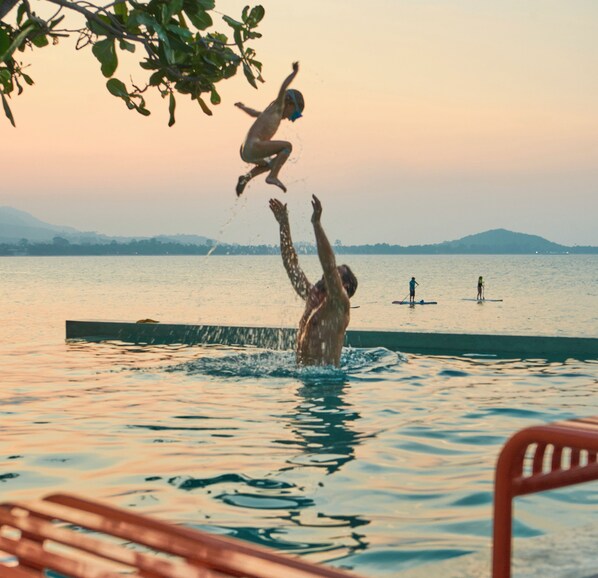 A person jumping into a pool with another person in the background. - Escape Beach Resort (Koh Samui)