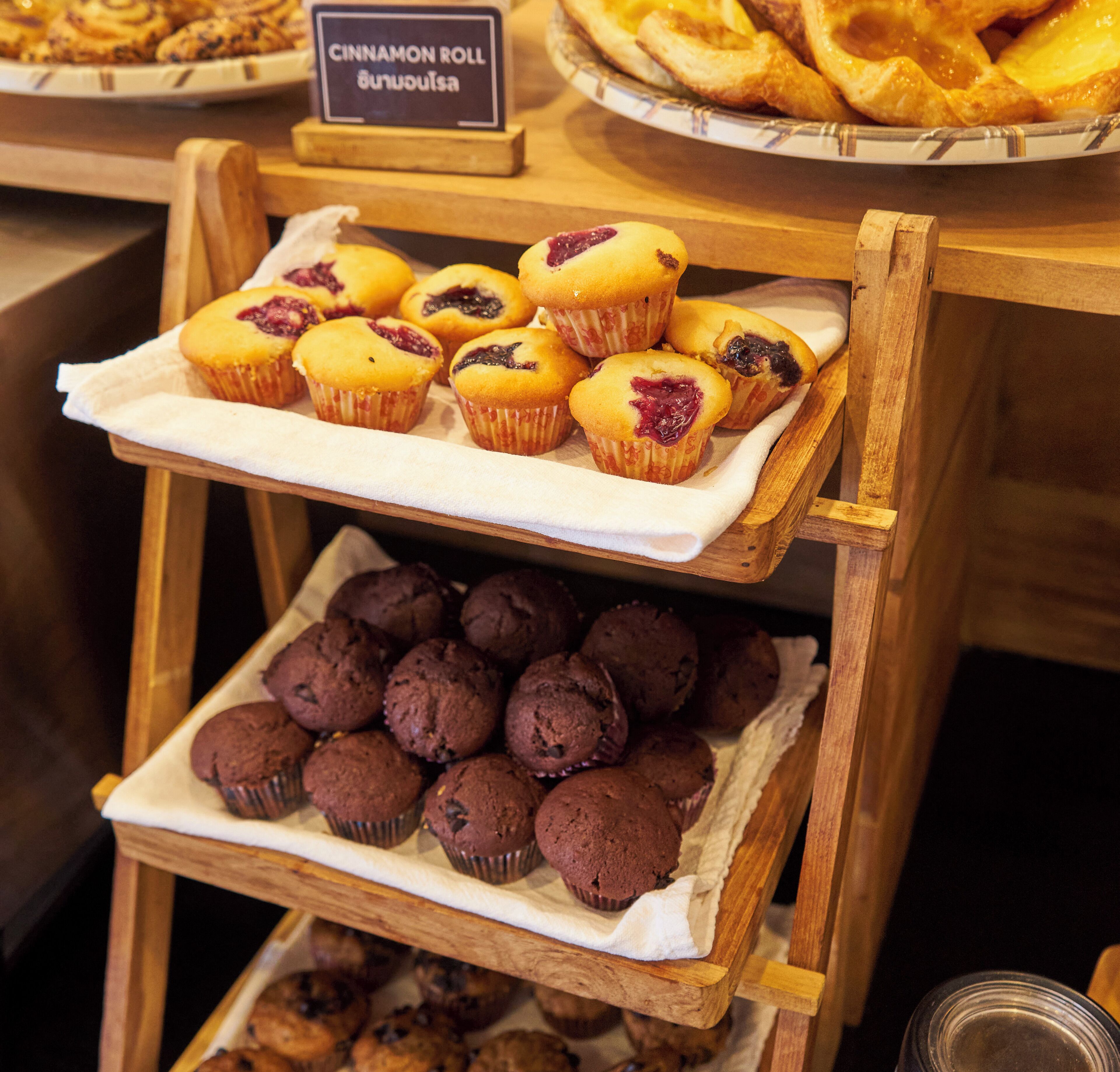 A display of muffins and pastries on a wooden stand.
