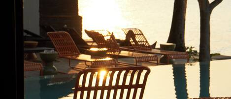 A poolside area with lounge chairs and a view of the water.
