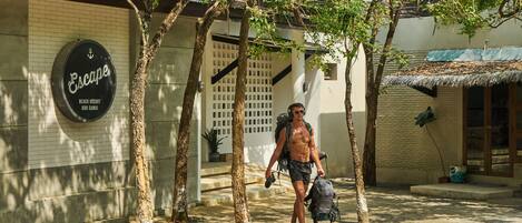 Un hombre camina hacia un edificio con un letrero que dice "Escape Beach Resort Koh Samui".