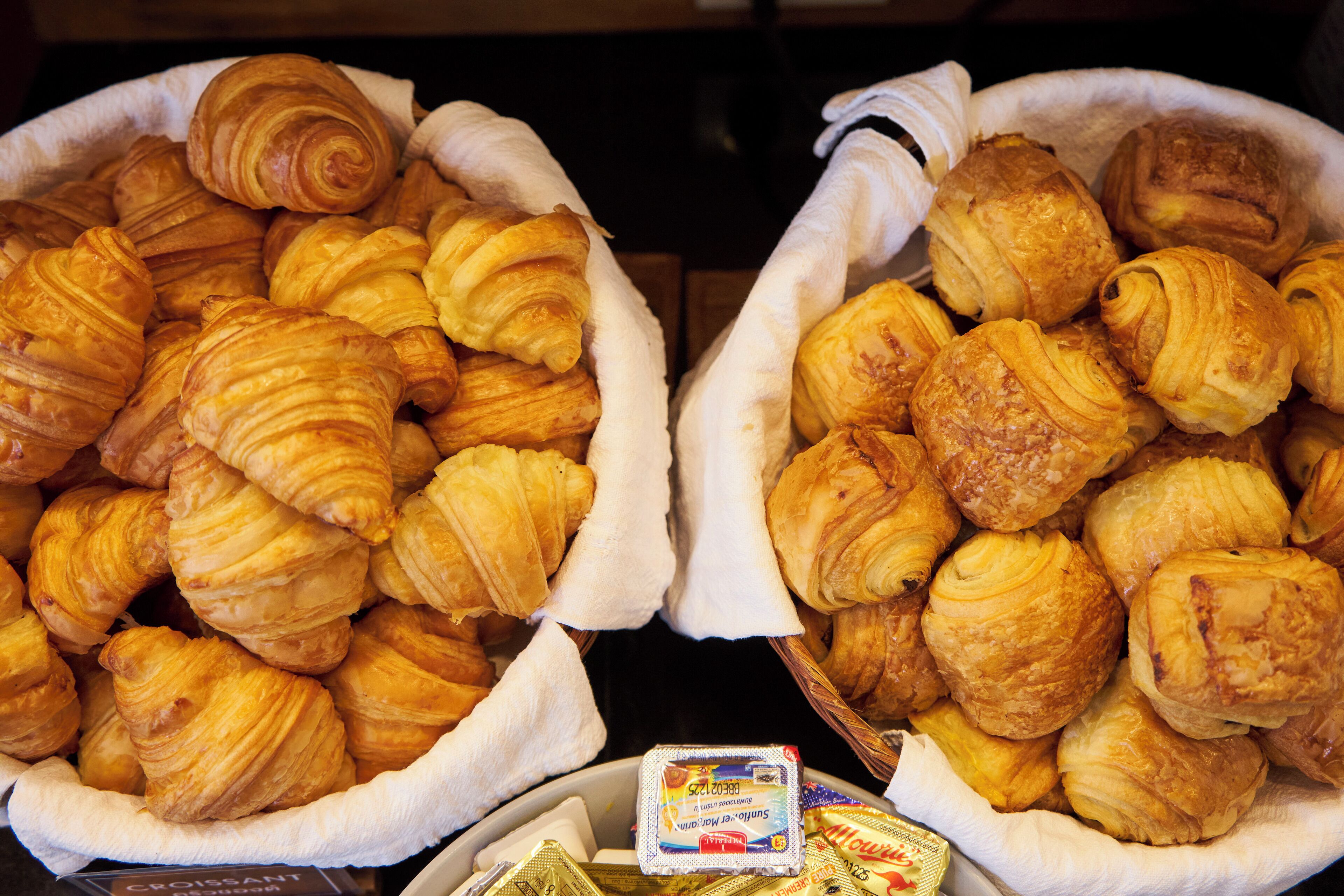 Two baskets filled with croissants and a small container of butter.