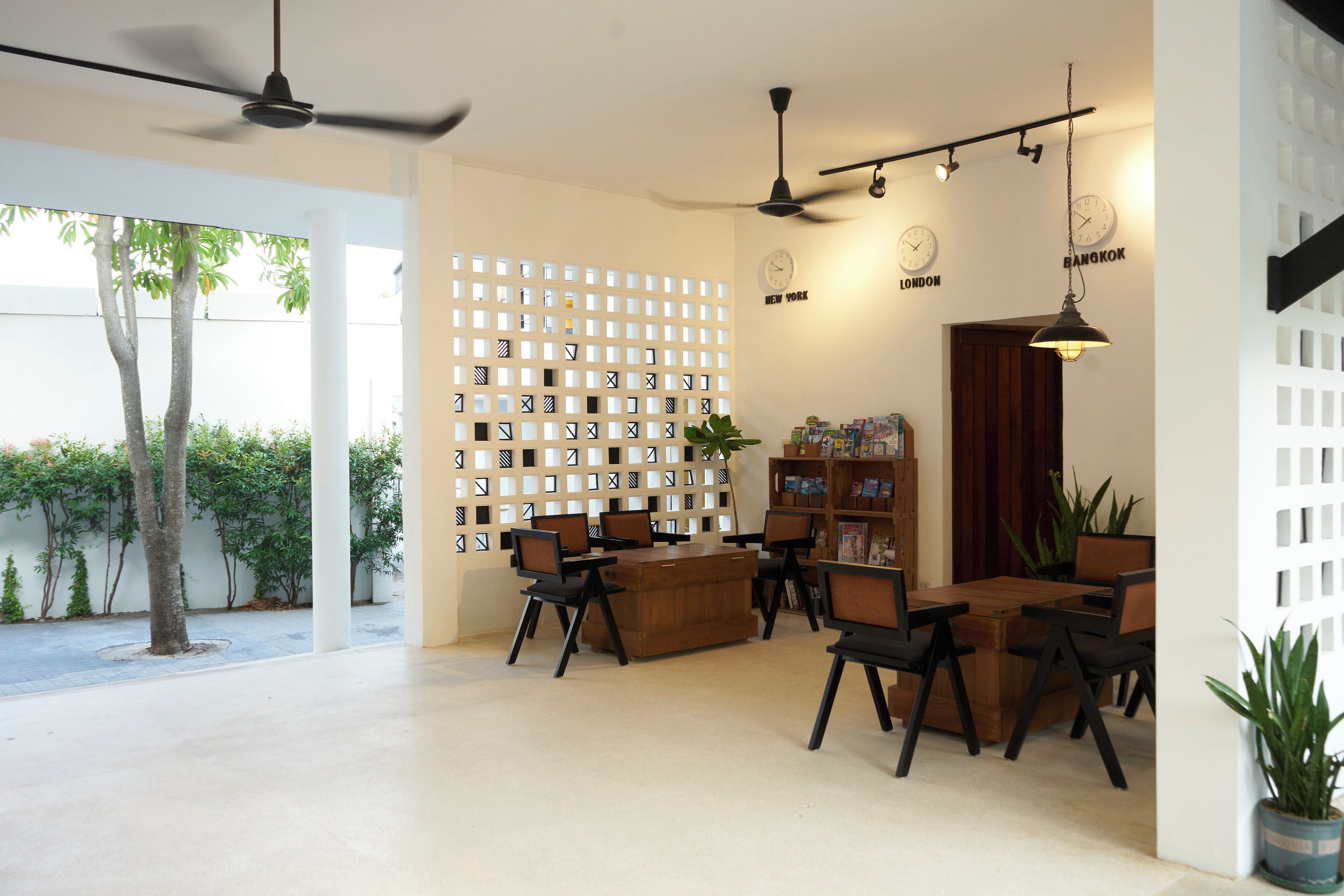 A spacious room with a wooden desk, chairs, a bookshelf, and a decorative wall with city names.