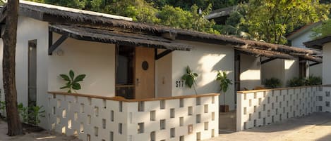 A modern building with a thatched roof, a number 'S17' on the wall, and a lattice fence.