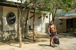 Un hombre caminando frente a un edificio con un letrero que dice "Escape Beach Resort Koh Samui".