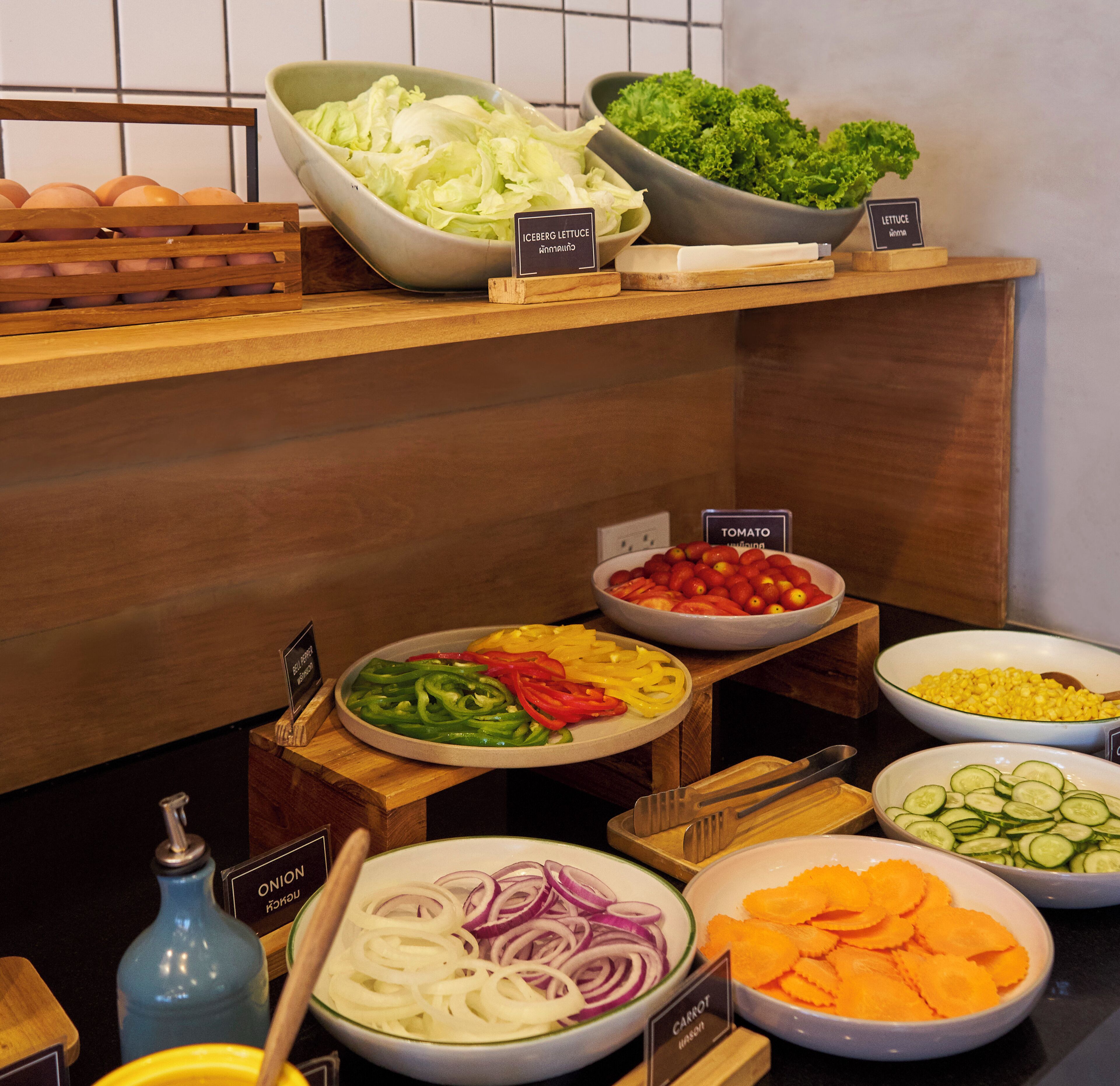 Un bufé con distintos alimentos, como verduras, frutas y huevos.