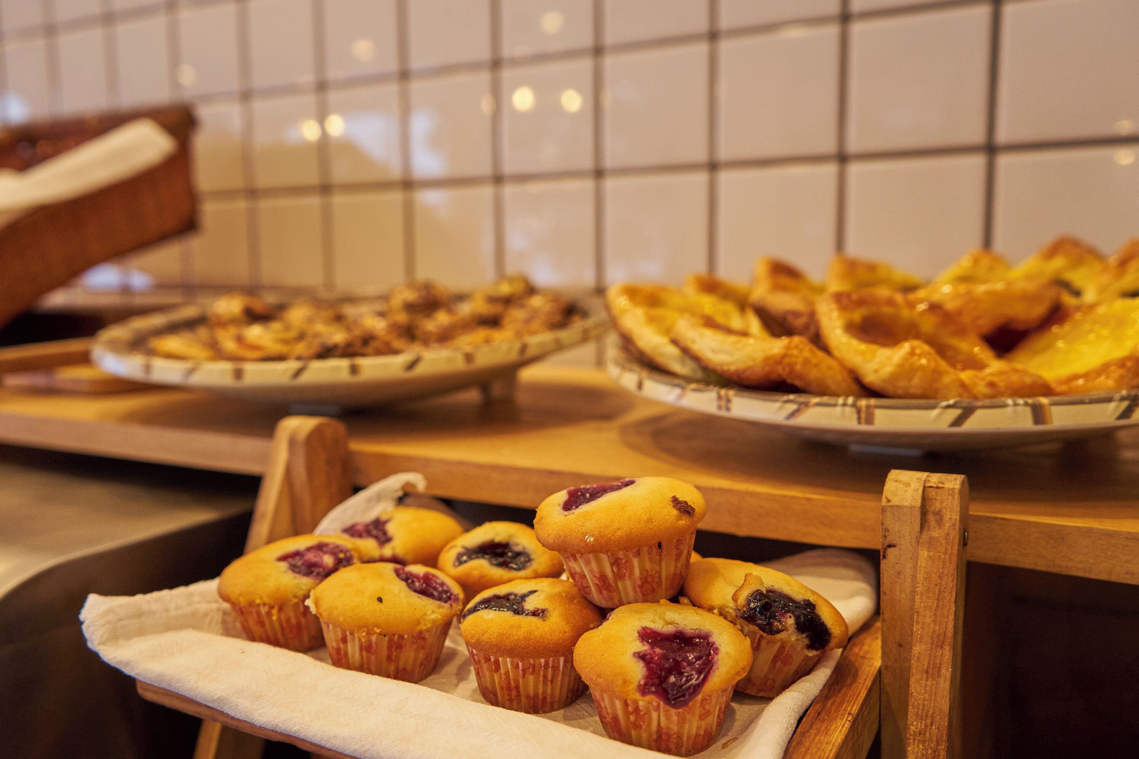 A tray of muffins and pastries on a wooden counter.