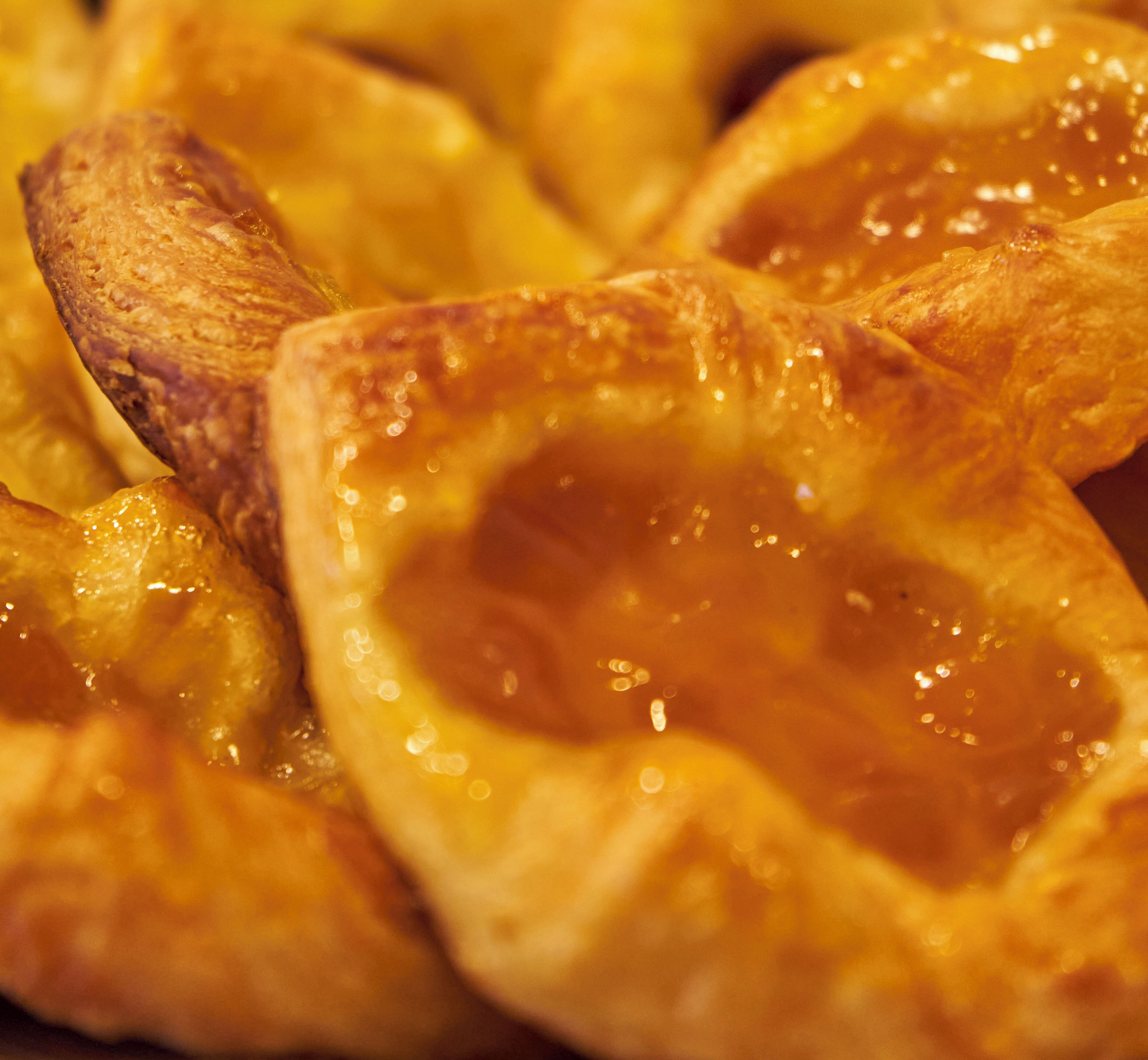 A close-up of a baked pastry with a golden-brown crust and a glossy, caramelized surface.