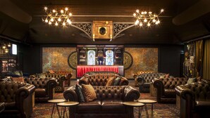 A luxurious lounge area with leather sofas, a red curtain, and ornate wall decorations.