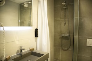 Un baño con lavamanos, espejo, ducha e inodoro.
